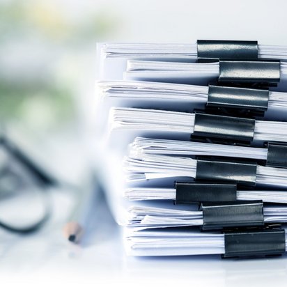 Some objects are zoomed in on a table, to the left is a pile of documents. In the centre is a pencil. On the far left is a pair of glasses. Some objects are zoomed in on a table, to the left is a pile of documents. In the centre is a pencil. On the far left is a pair of glasses.