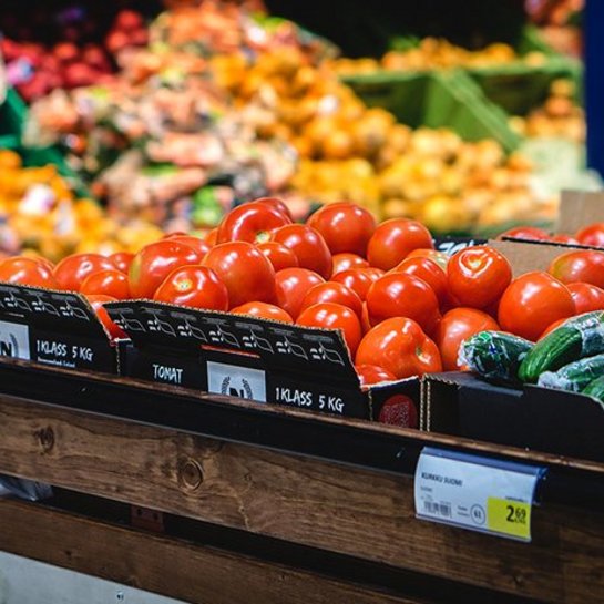 Fresh tomatoes and cucumbers displayed in a grocery store produce section.