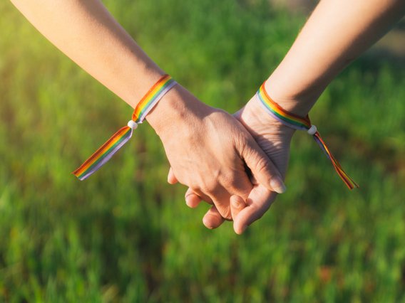Two people are holding hands while wearing LGBTQIA+ pride bracelets Two people are holding hands while wearing LGBTQIA+ pride bracelets