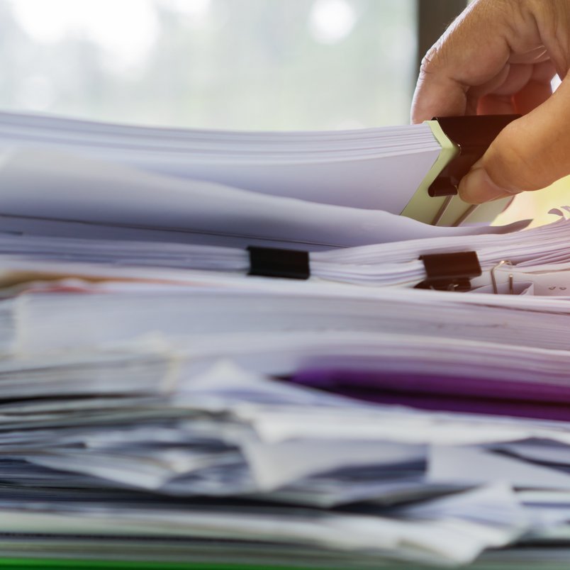 A pile of documents is zoomed in, a person is browsing the pile.