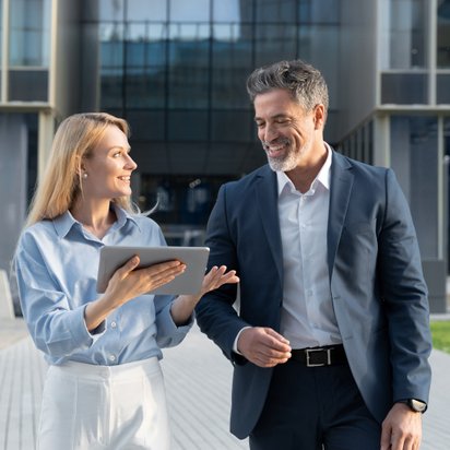 Zwei Personen gehen nebeneinander und besprechen ein Projekt Zwei Personen gehen nebeneinander und besprechen ein Projekt