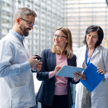 Bilden visar en person som samtalar med två läkare i en klinisk miljö