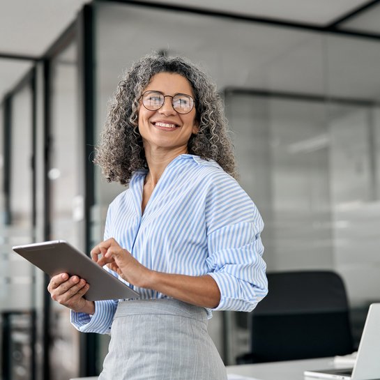 Femme professionnelle utilisant une tablette dans un bureau moderne.