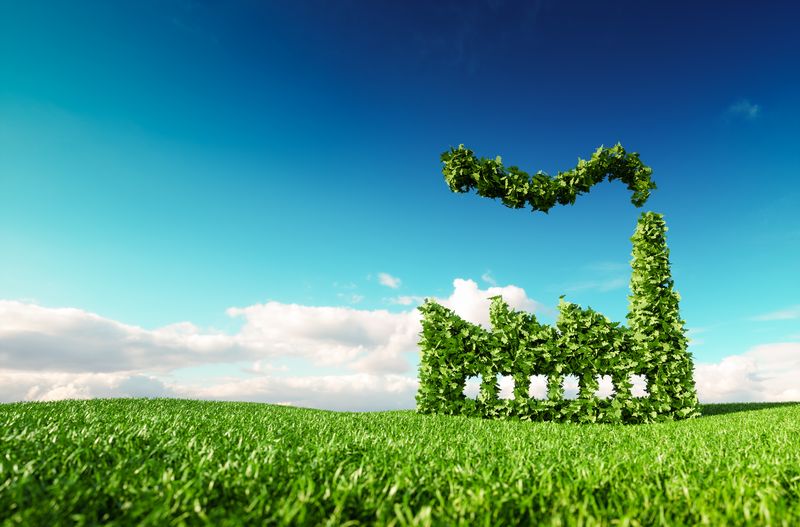 Eco friendly industry concept. 3d rendering of green factory icon on fresh spring meadow with blue sky in background. ISO 14001:2015 Miljöledningssystem