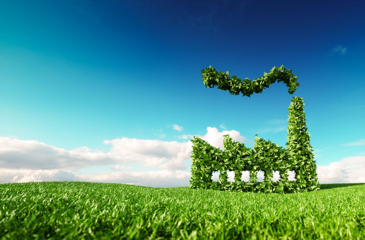 Eco friendly industry concept. 3d rendering of green factory icon on fresh spring meadow with blue sky in background. ISO 14001:2015 Miljöledningssystem