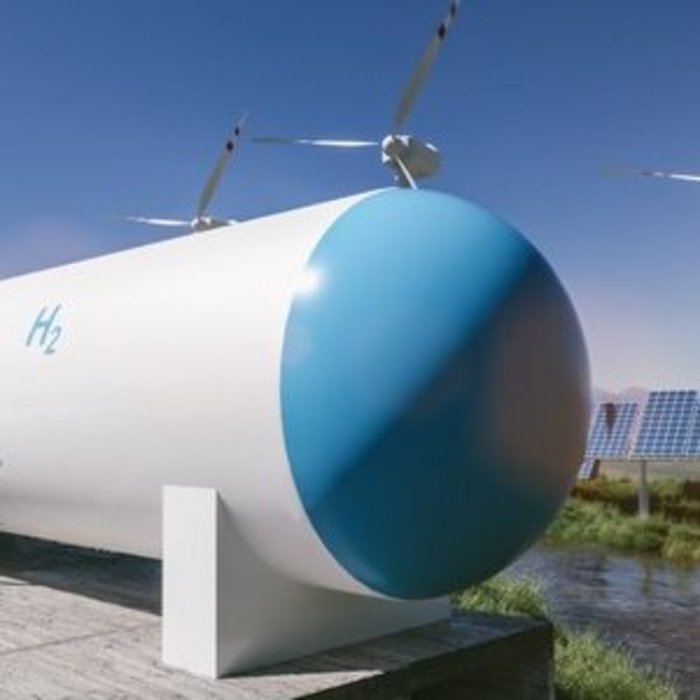 Wasserstofftank mit Aufschrift H₂ neben Windrädern und Solaranlagen zur nachhaltigen Energiegewinnung.