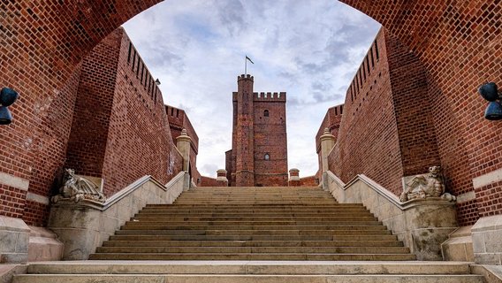 The iconic Kärnan tower rises majestically, framed by grand brick arches, showcasing Helsingborg's history and architectural beauty.