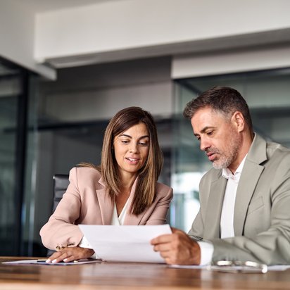 Two coworkers discussing a document in an office.