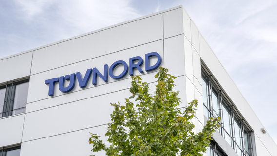 TÜV NORD logo on sleek, modern building surrounded by greenery.