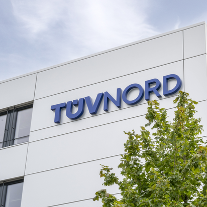 TÜV NORD logo on sleek, modern building surrounded by greenery.