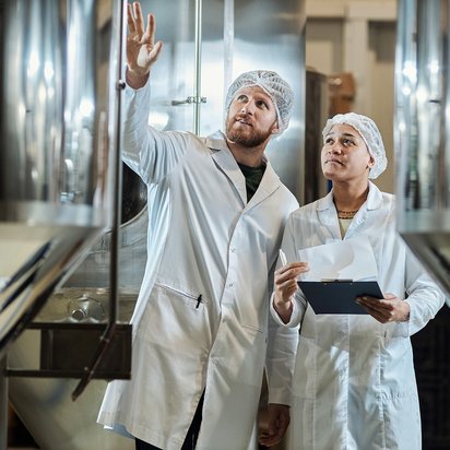 TÜV NORD Lead Auditor Course FSSC 22000 v7 Two food auditors are checking a food container in a factory