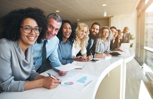 690855708 Cheerful multiracial colleagues looking at camera in office